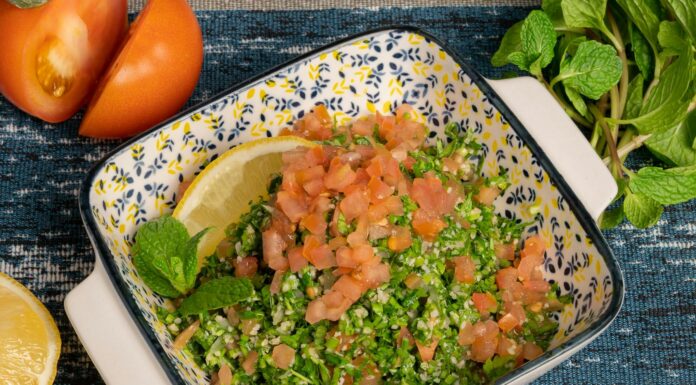a bowl of salad with tomatoes parsley and lemon