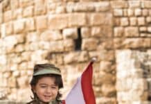 little boy wearing a military uniform holding a lebanese flag