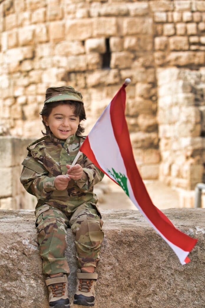 little boy wearing a military uniform holding a lebanese flag