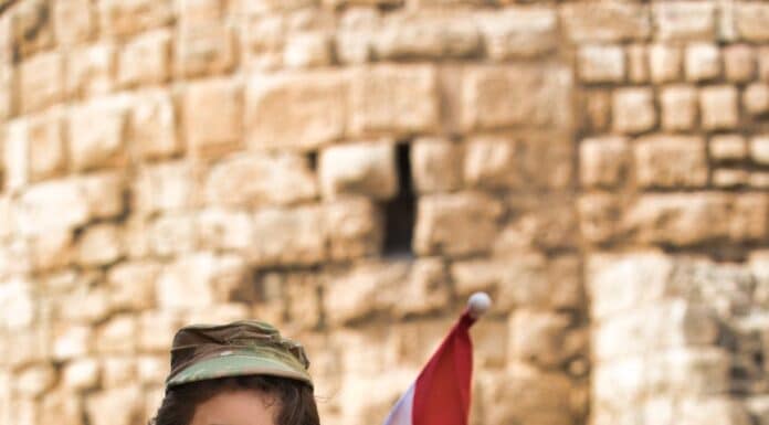 little boy wearing a military uniform holding a lebanese flag