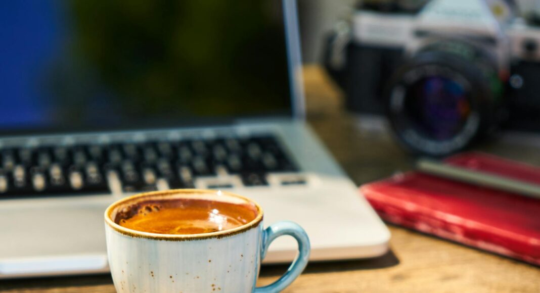 a cup of coffee and a camera on a wooden table in the workplace