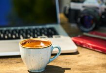 a cup of coffee and a camera on a wooden table in the workplace