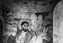 a black and white photo of a man riding on a donkey