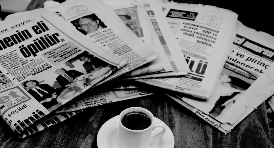 folded newspapers and a cup of coffee