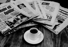 folded newspapers and a cup of coffee