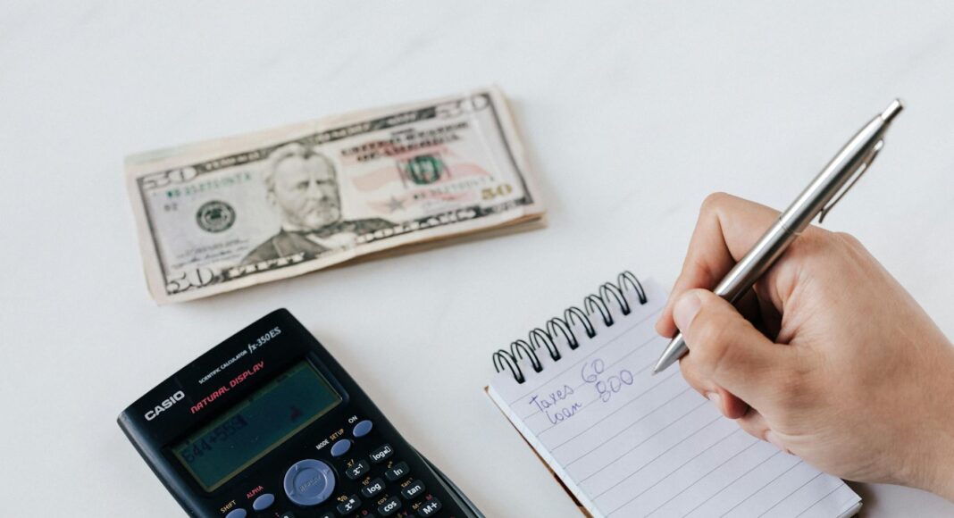 crop anonymous financier planning budget writing numbers in notebook