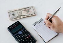 crop anonymous financier planning budget writing numbers in notebook