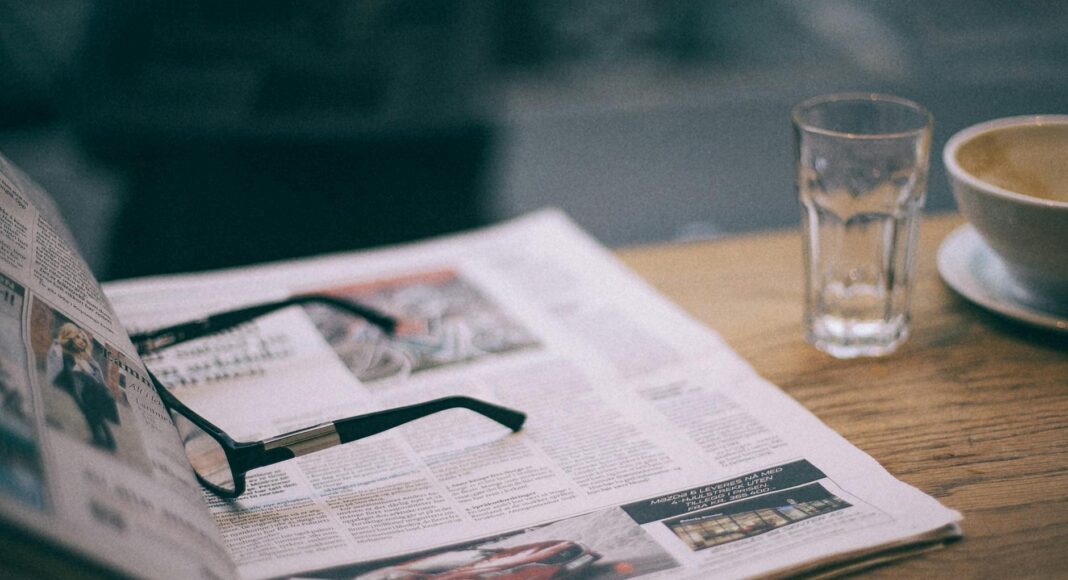 eyeglasses on magazine near glass on cafe table