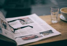eyeglasses on magazine near glass on cafe table