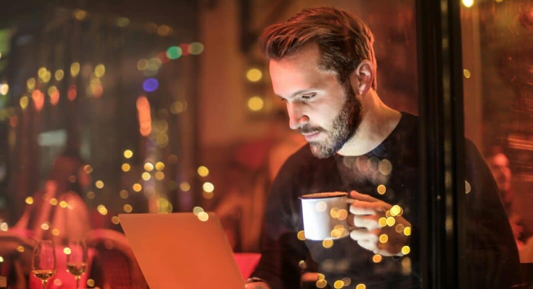 man holding mug in front of laptop