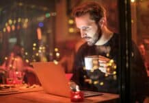 man holding mug in front of laptop