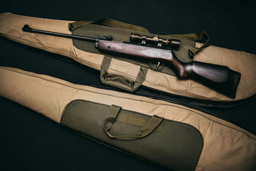 black rifle with scope and brown gig bag