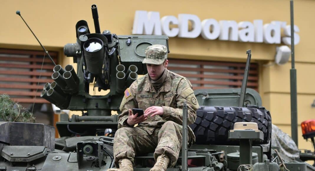 man in brown camouflage sitting on top of tank