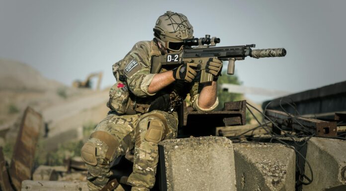 soldier near concrete pillars holding semi automatic gun with scope