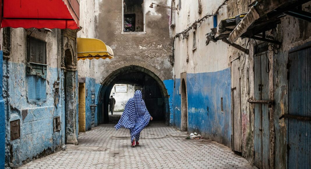 back of a woman wearing a polka dot jilbab walking along a paved alley