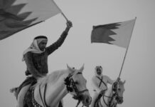 two men riding horses with bahraini flags in hands