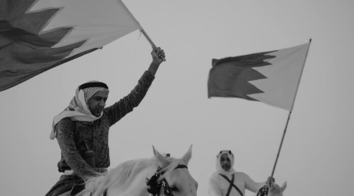 two men riding horses with bahraini flags in hands