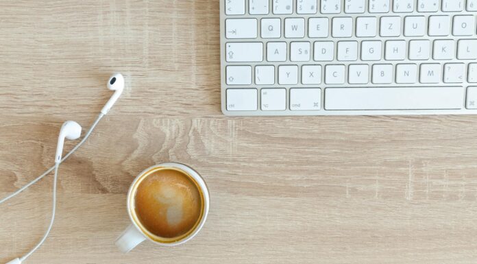 beverage filled mug near apple airpods with lightning connector and apple magic keyboard