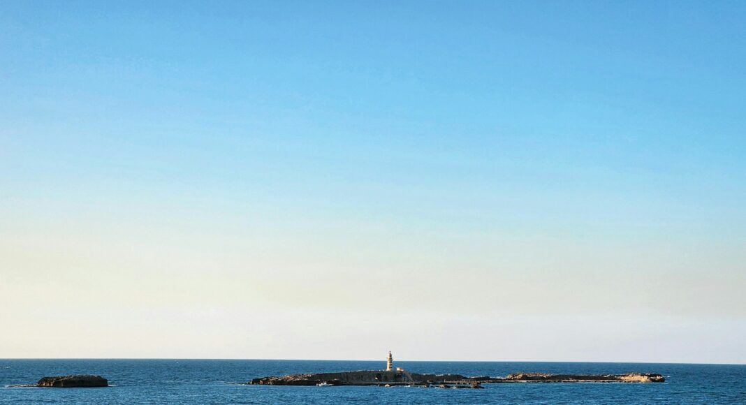 a large body of water with a light house in the distance