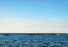 a large body of water with a light house in the distance