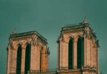 Faut-il faire payer l’entrée à Notre-Dame de Paris ? Entre préservation et gratuité sacrée a large building with a clock on it with Notre Dame de Paris in the background