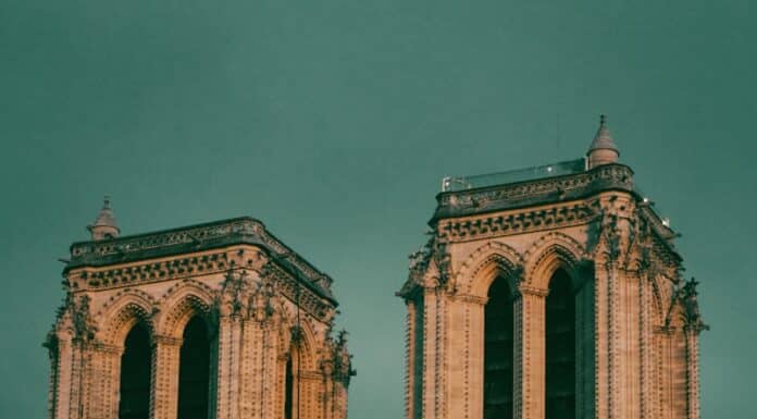 a large building with a clock on it with Notre Dame de Paris in the background