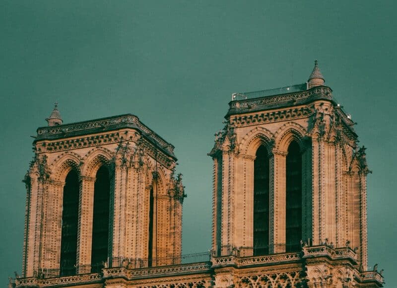 a large building with a clock on it with Notre Dame de Paris in the background