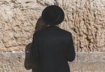 Revue de presse israélienne: négociations difficiles avec le Liban a man wearing a black hat standing in front of a stone wall