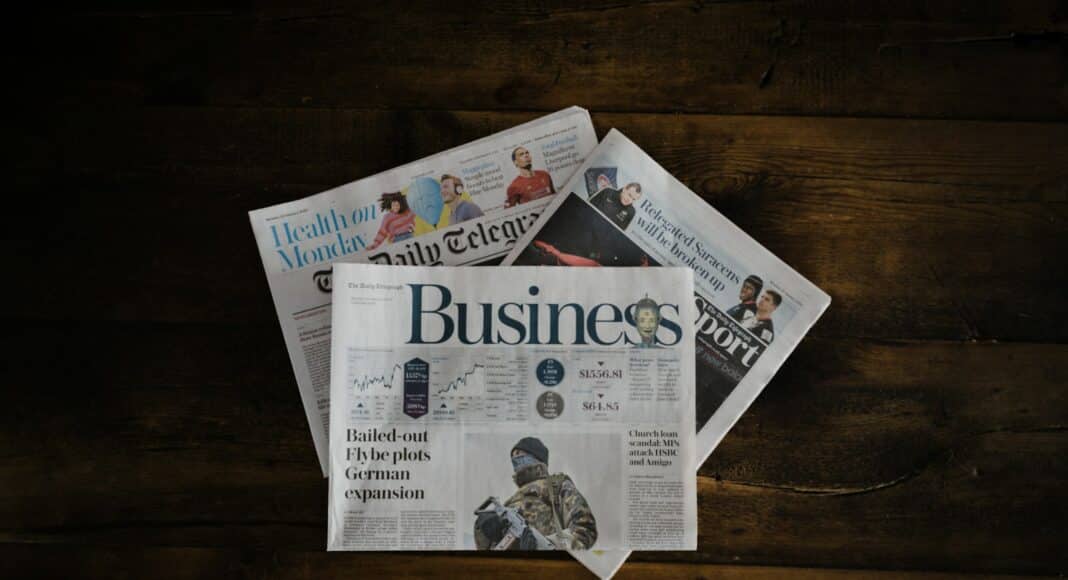 a stack of newspapers sitting on top of a wooden table