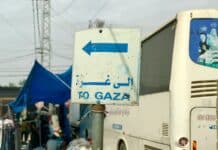 a white bus parked next to a blue and white sign
