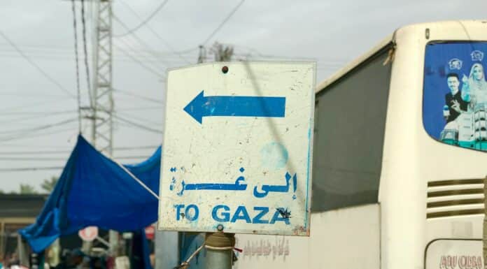 a white bus parked next to a blue and white sign