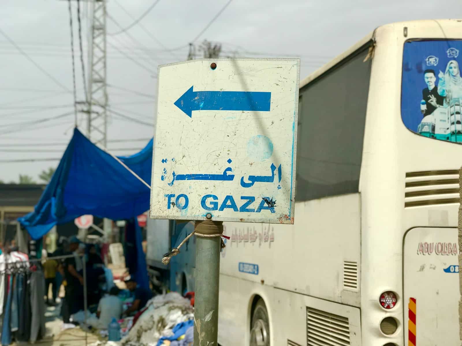 La Ligue des Tartuffes a white bus parked next to a blue and white sign