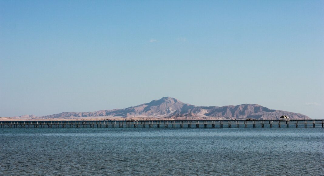 blue sea near mountain under blue sky during daytime