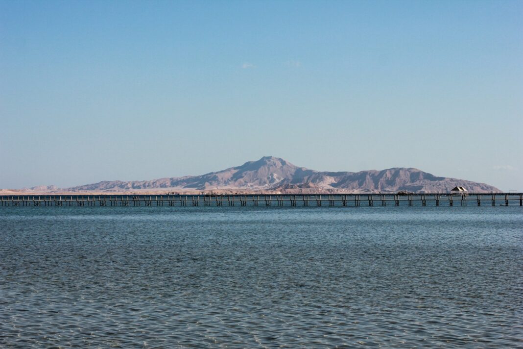 blue sea near mountain under blue sky during daytime