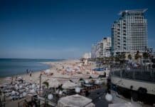 Revue de presse israélienne: Tensions sécuritaires en Israël, affrontements et menaces persistantes a crowded beach with umbrellas and buildings in the background