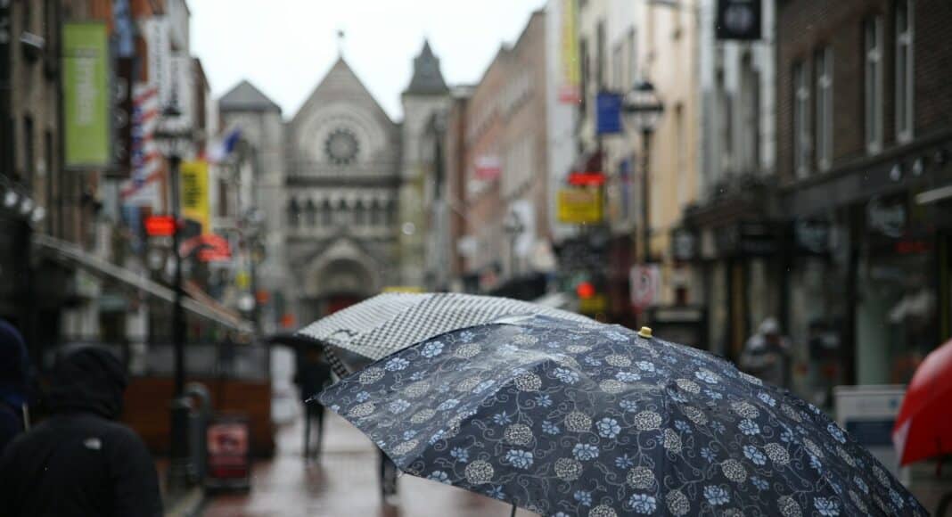 person holding floral umbrella between buildings