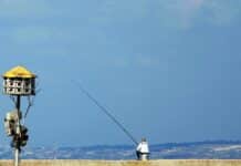 a man fishing on a lake with a tower in the background