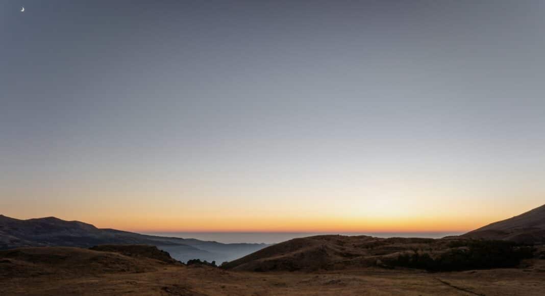The sun is setting over a mountain range