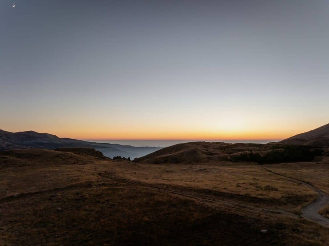 The sun is setting over a mountain range