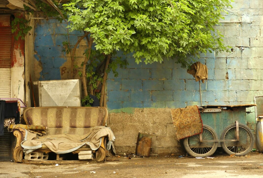 a dirty couch sitting next to a tree in front of a building