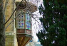 a building with a stained glass window and a tree in front of it