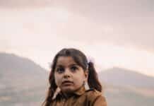 girl in brown jacket holding flag