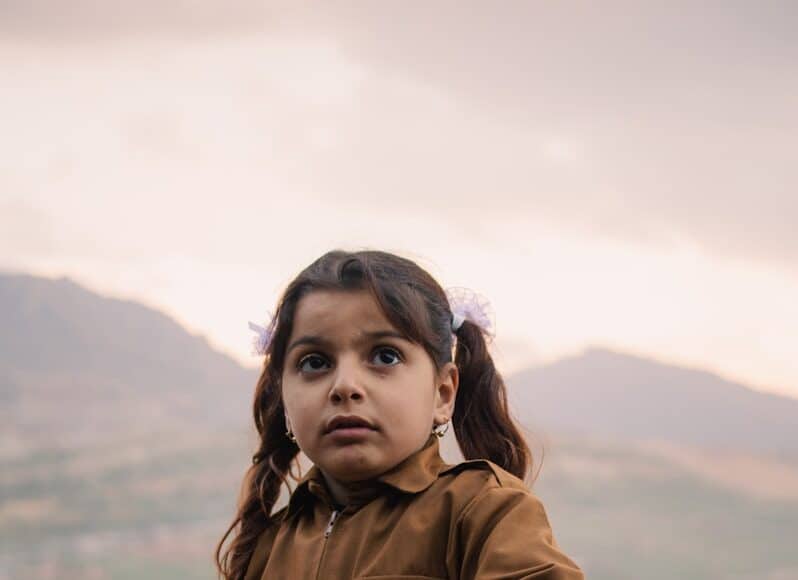 girl in brown jacket holding flag