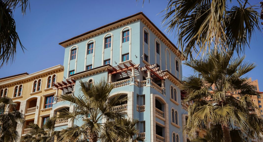 a tall blue building with palm trees in front of it