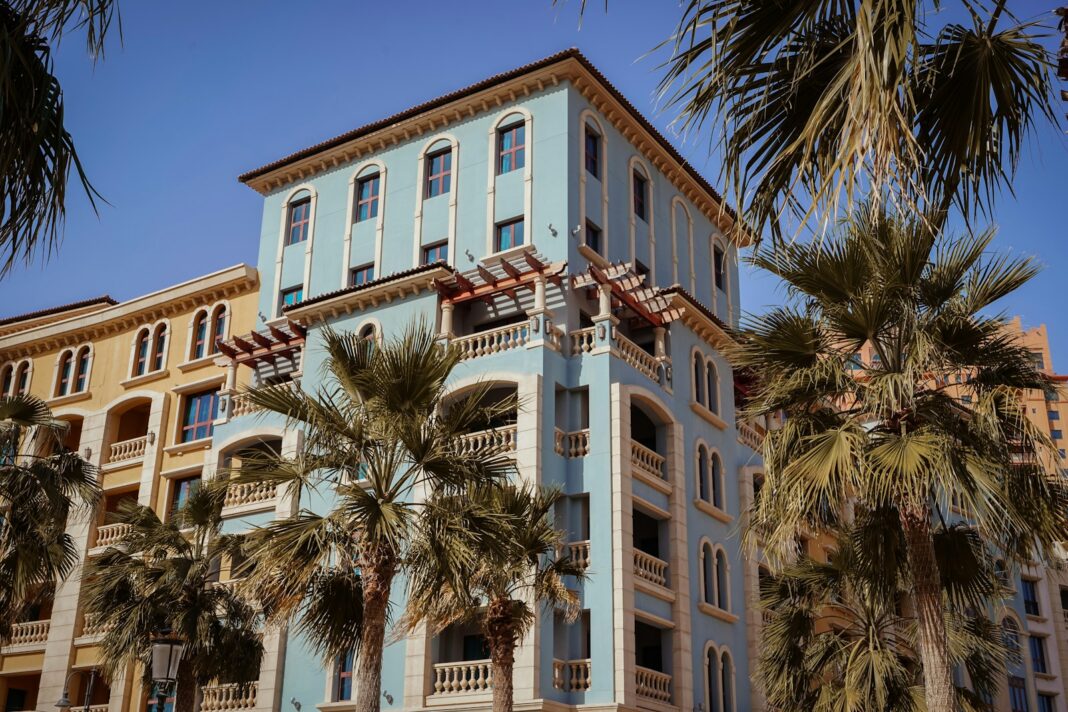 a tall blue building with palm trees in front of it