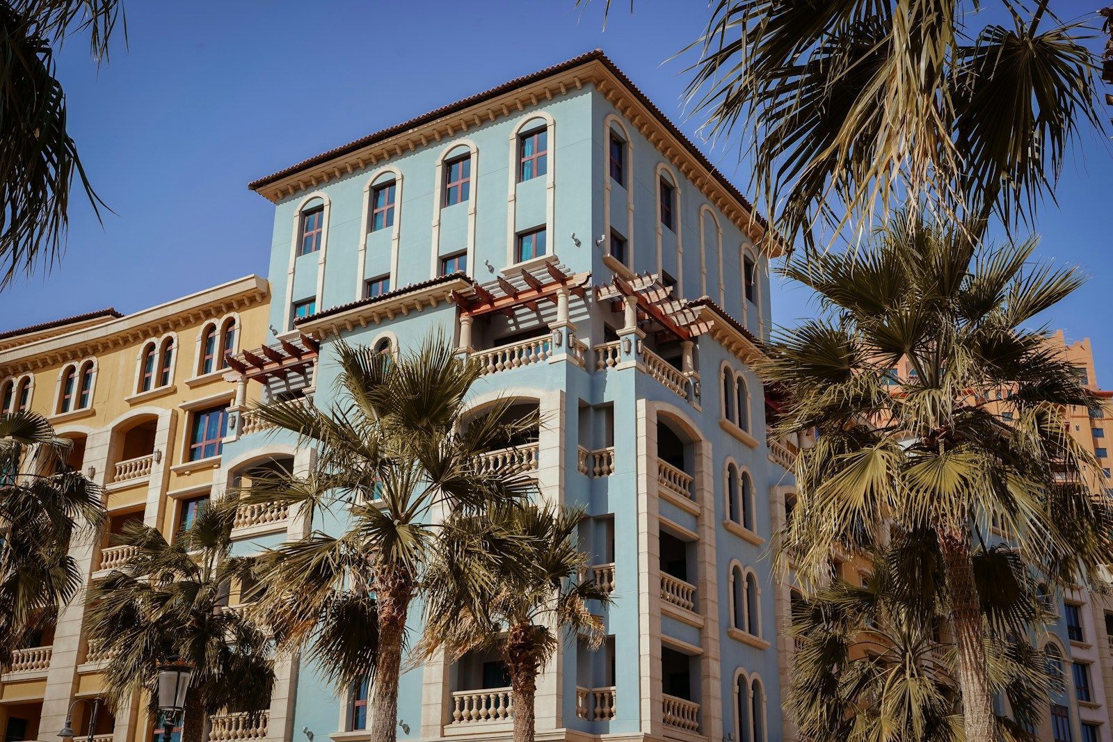 Israël, Qatar, Égypte : une médiation cruciale au cœur des négociations avec le Hamas a tall blue building with palm trees in front of it