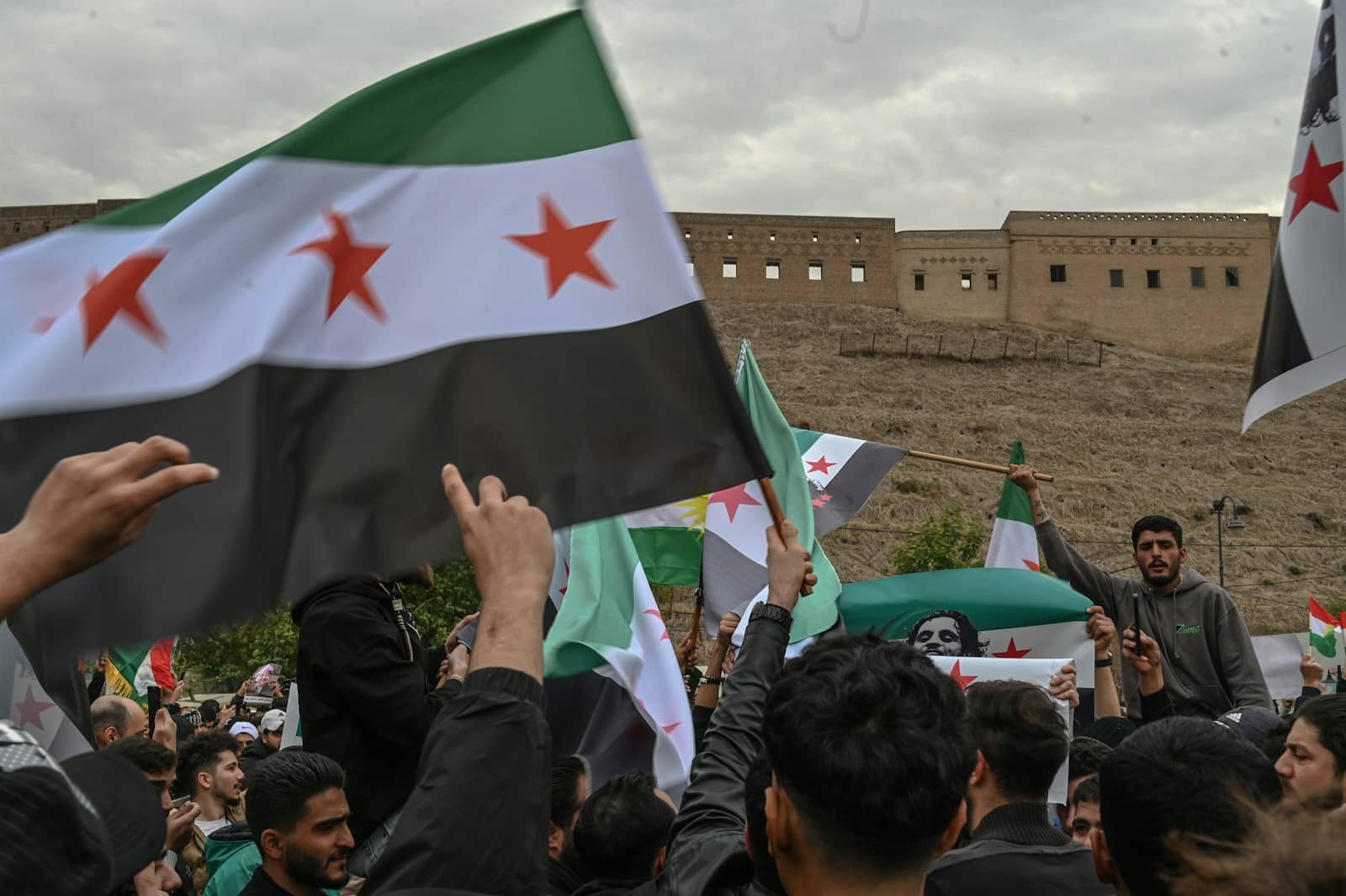 Syrie : Mohammed Ghazi Jalali appelle à une transition rapide après la chute du régime d’Assad A group of people holding flags in front of a building