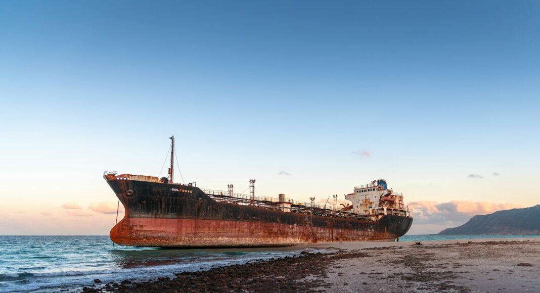 a rusted ship sitting on top of a sandy beach