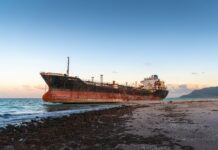 a rusted ship sitting on top of a sandy beach