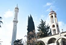 a tall white clock tower sitting next to a tall white building